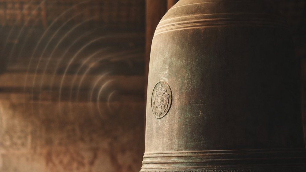 Weathered bronze temple bell, illustrating structural resonance and vibration in bone tapping practice