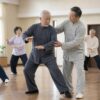 Instructor guiding an elderly man's balance in a community Tai Chi class
