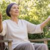Woman in a headscarf practicing gentle seated Qigong in a garden
